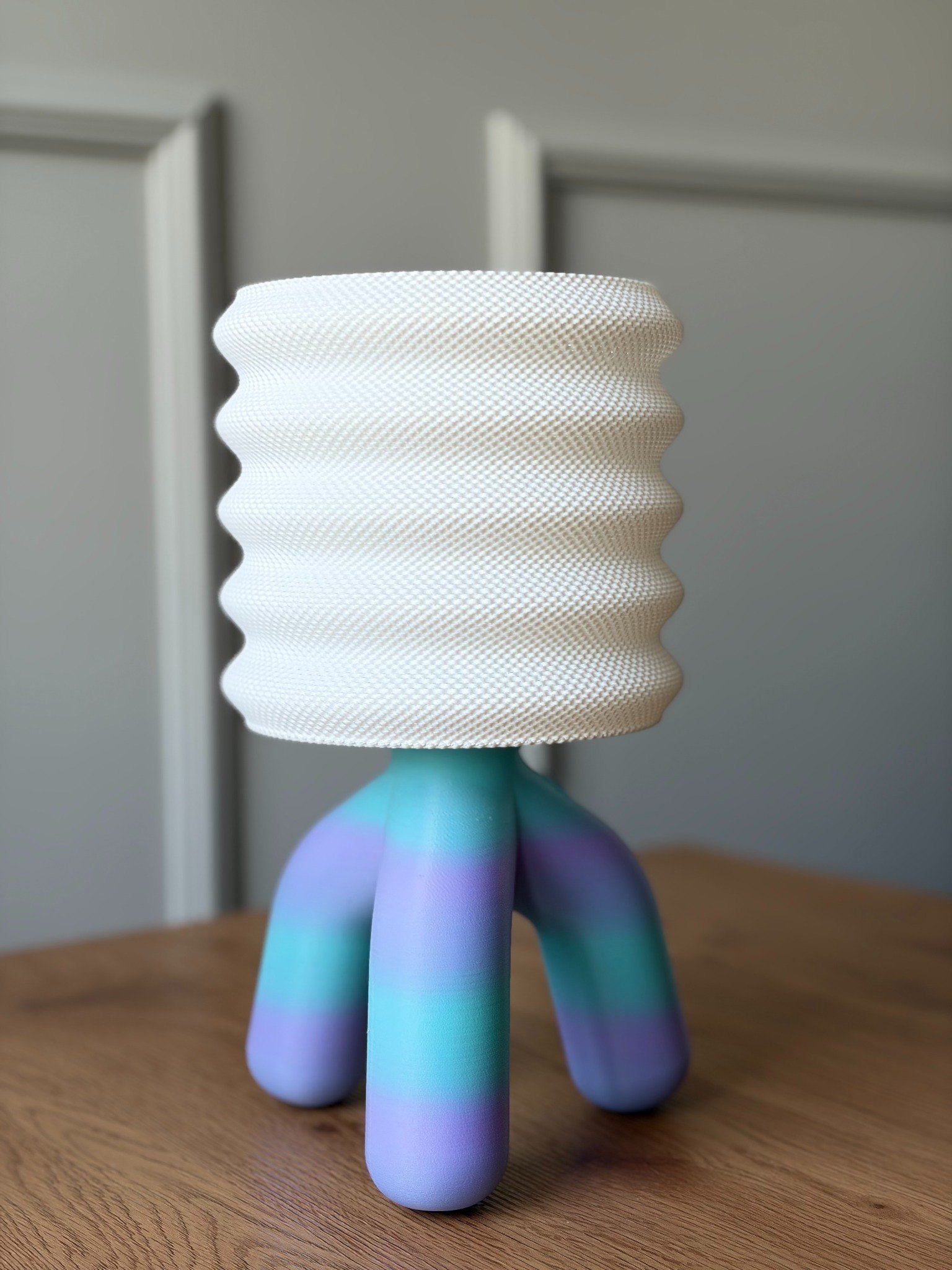 Blueberry lamp: a rippled white shade on a curving three-legged base in blue and lilac